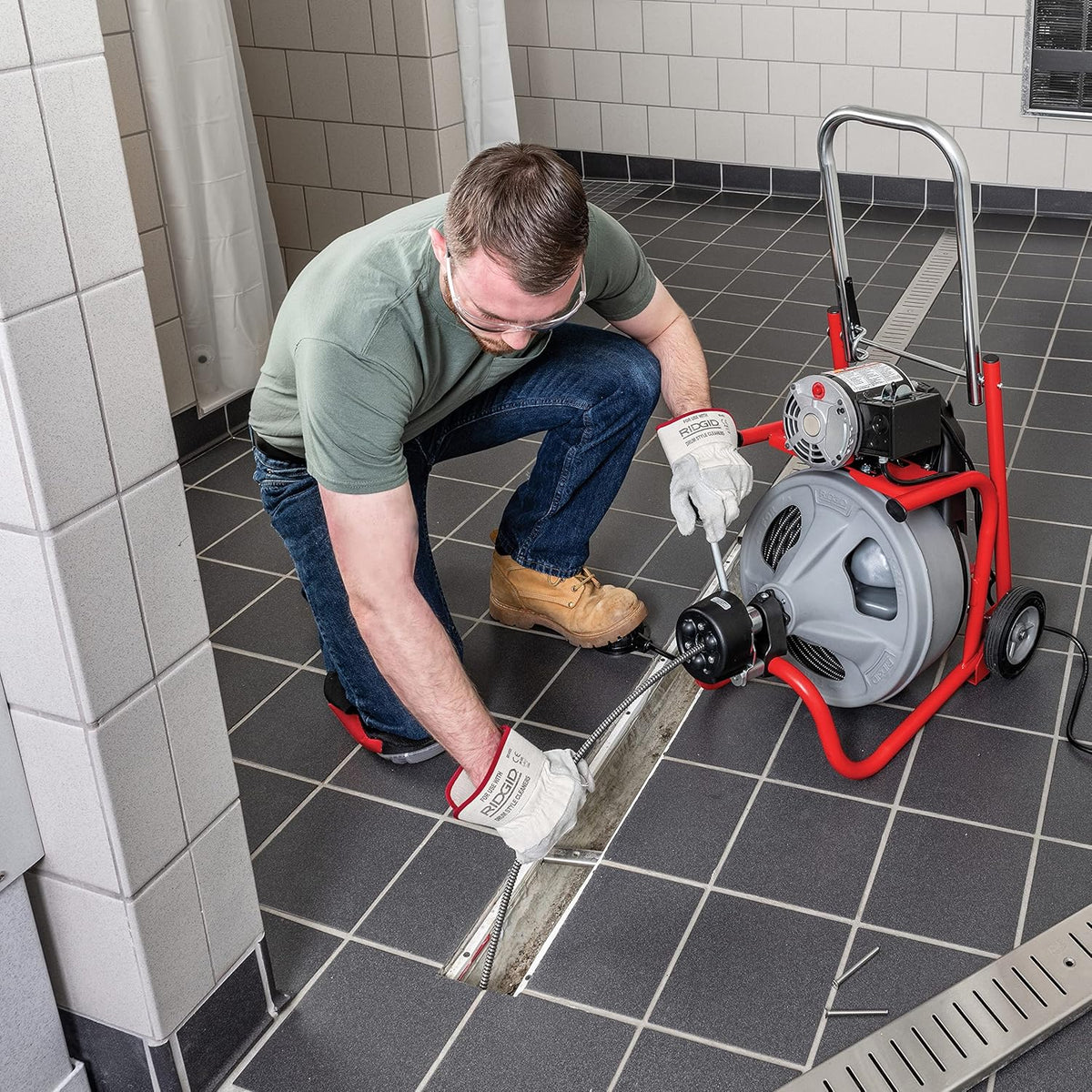 Person using a tool on a concrete surface to remove drain clogs